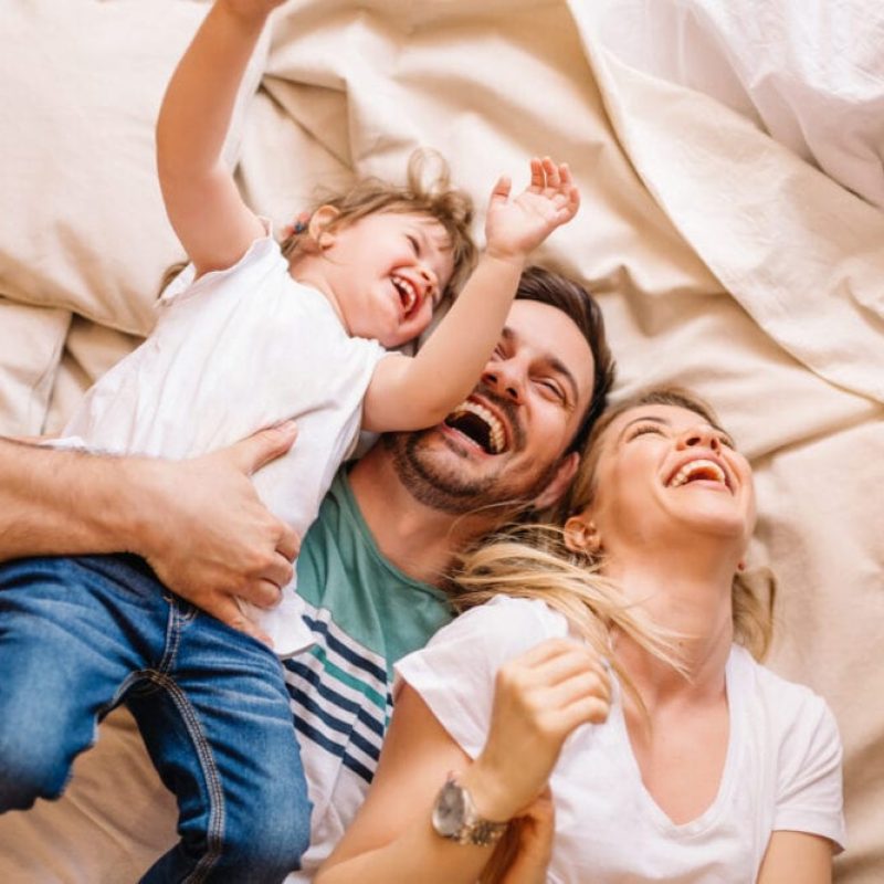 Happy,Family,Having,Fun,In,The,Bedroom,While,They,Lie